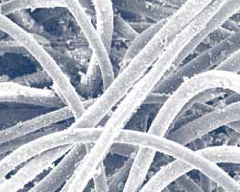 These photos were taken with a scanning electron microscope of bag media used in a collector that was filtering fly ash. The bags were removed after 2,700 hours of use. Air-to-media ratio was 4.5 to 1. Pressure drop after 2,700 hours of operation was 6 in. (152.4 mm) on polyester bags and 2 in. (50.8 mm) on hydroentangled bags.